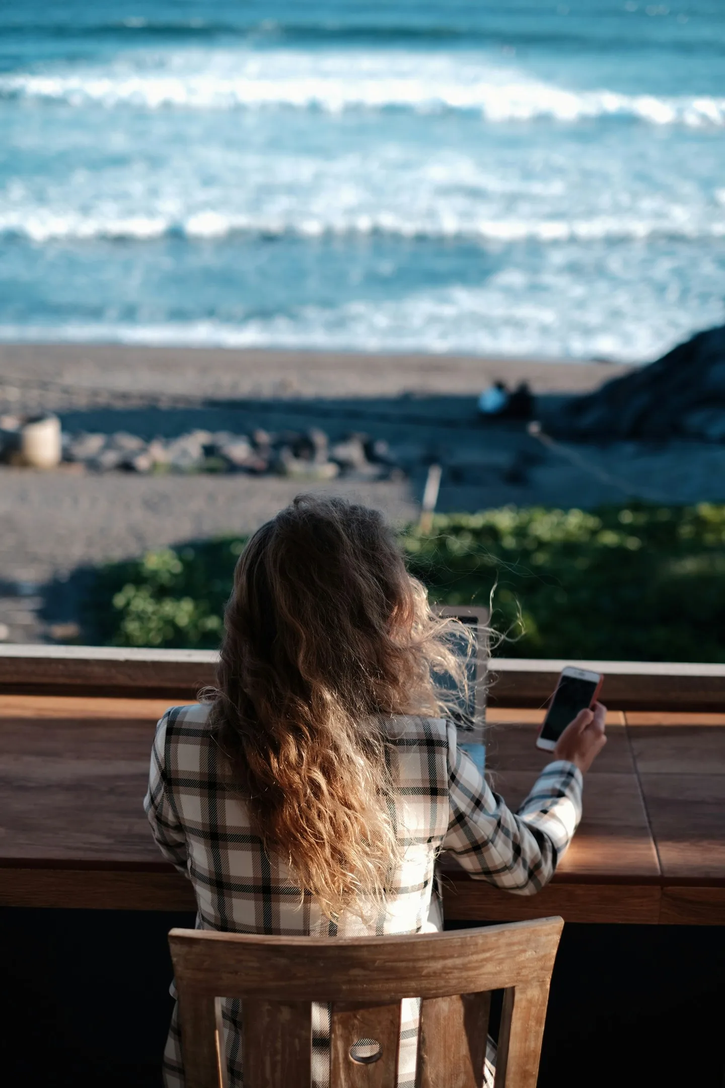 A woman sitting using a laptop in a beach bar